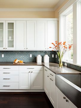Clean White Cabinets And Minimalist Drawer Pulls Couple With A Blue Tiled Backsplash And Warm Brown Countertops To Create A Welcoming Environment For Family And Friends To Gather. In The Forefront, A ...